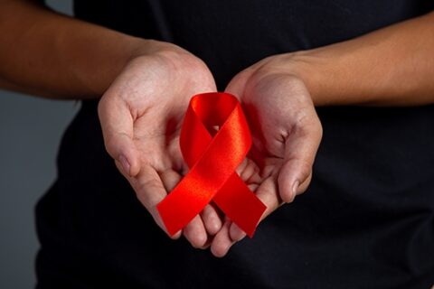 Woman hand holding red ribbon HIV awareness concept World AIDS D